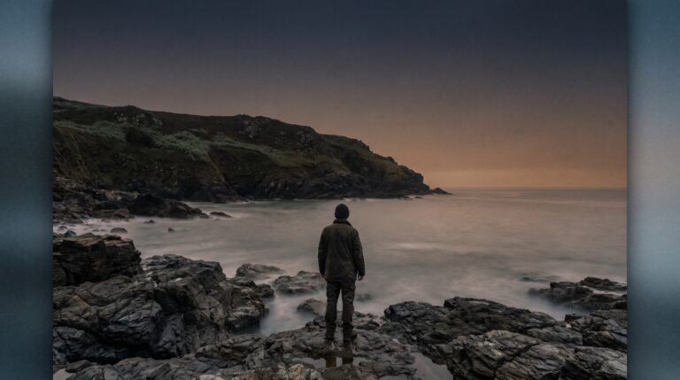 Lone figure on wet rocks watching a calm dawn sea, the mood behind these ocean and coast quotes