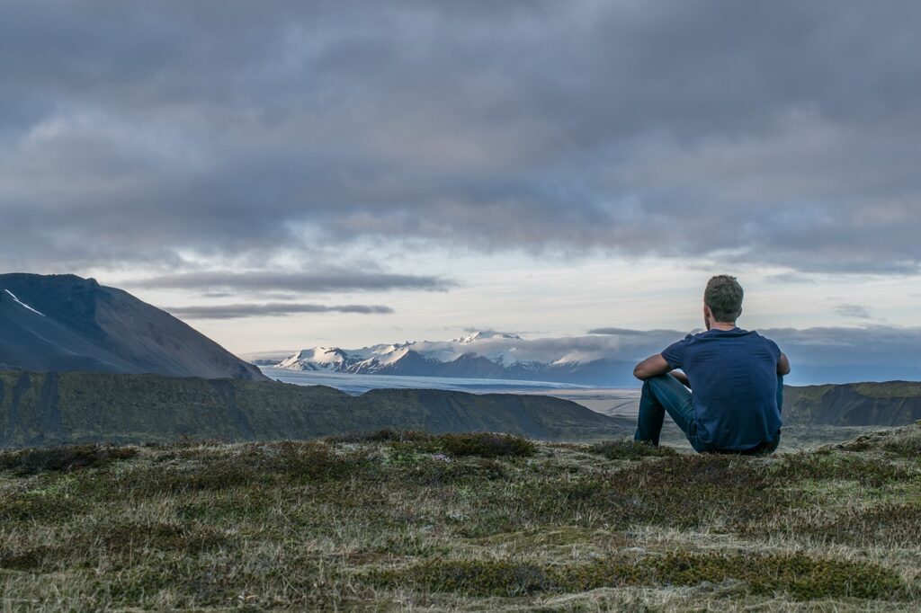 Man sitting and looking towards a mountain - Quotes About Traveling Solo