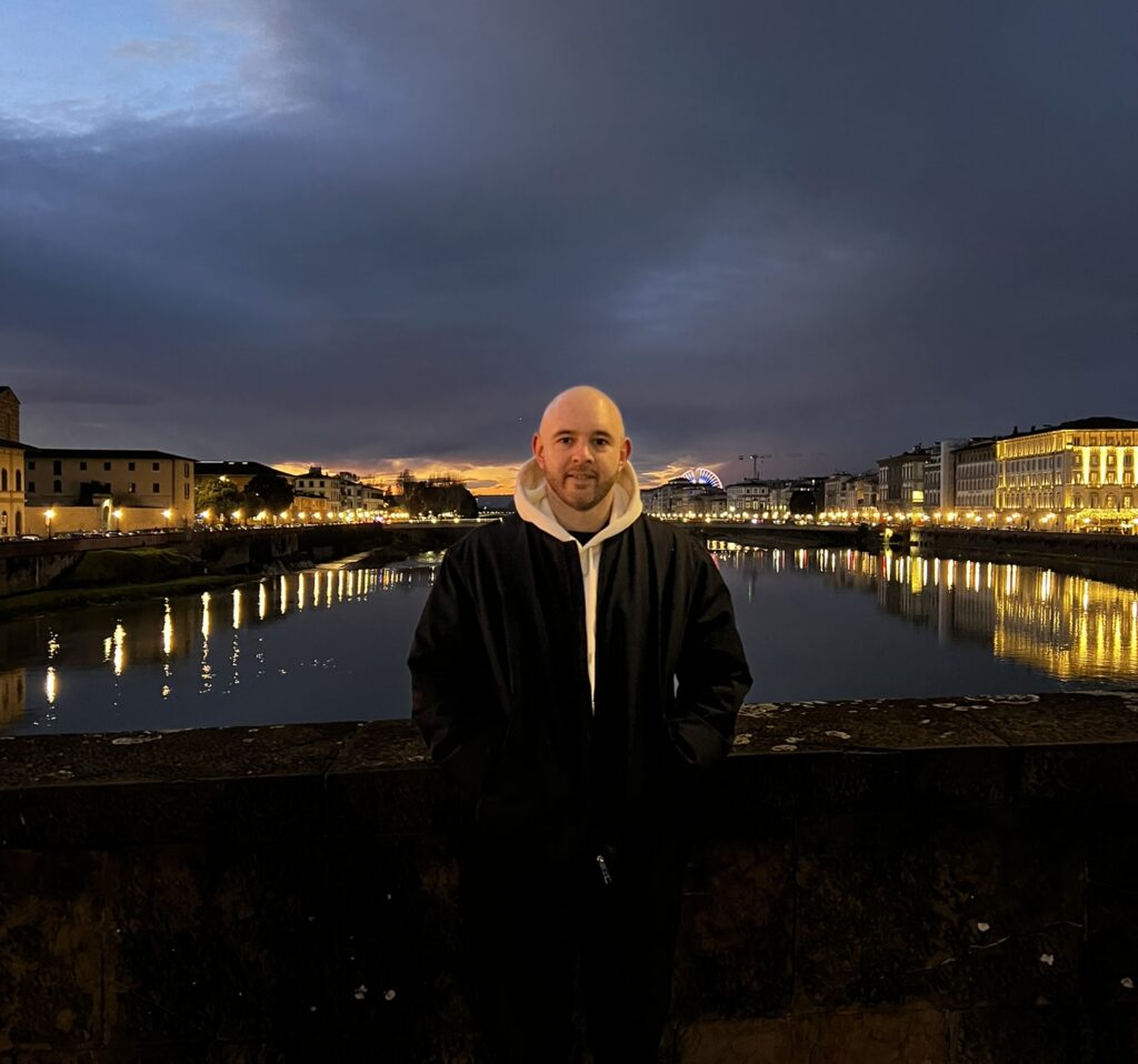 Standing on the Ponte Vecchio at dusk with the Arno and the city lights behind